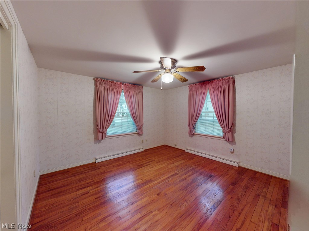 145 Overlook Road Painesville, OH 44077 - Photo 16 of 36 Spare room with wood-type flooring, a baseboard radiator, ceiling fan, plenty of natural light, and wallpapered walls