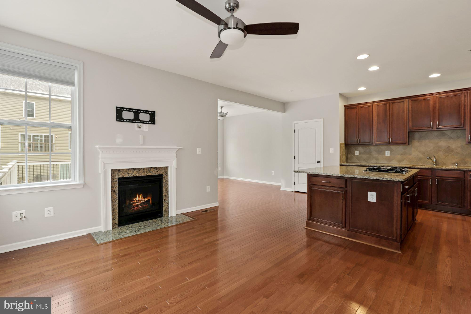 11007 Buggy Path Upper Marlboro, MD 20772 - Photo 5 of 18 a open kitchen with granite countertop a stove top oven a sink dishwasher and a fireplace with wooden floor