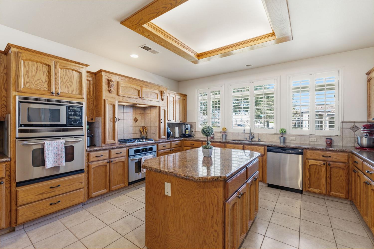 3296 Hollow Avenue Madera, CA 93637 - Photo 14 of 45 a kitchen with stainless steel appliances granite countertop a sink and dishwasher a stove with wooden cabinets