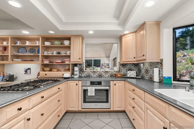 a open kitchen with stainless steel appliances granite countertop a stove a sink a dining table and chairs with wooden floor