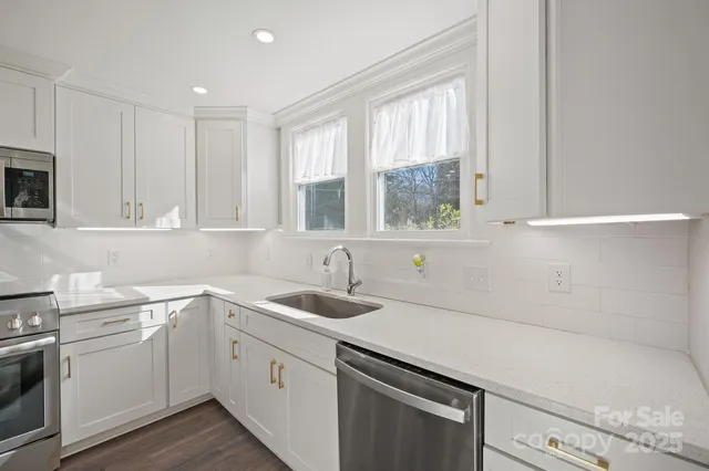 a kitchen with a sink white cabinets and white appliances