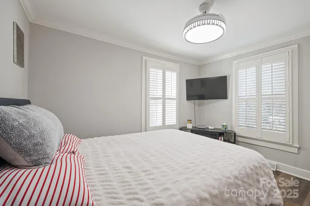 a bedroom with a bed window and a flat tv screen on dresser