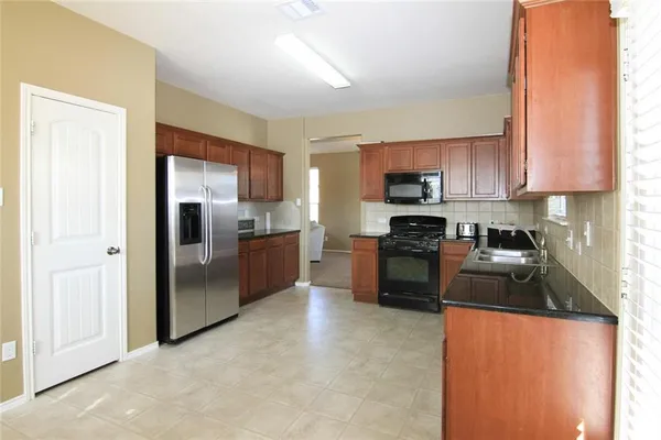 a kitchen with granite countertop a refrigerator and a sink