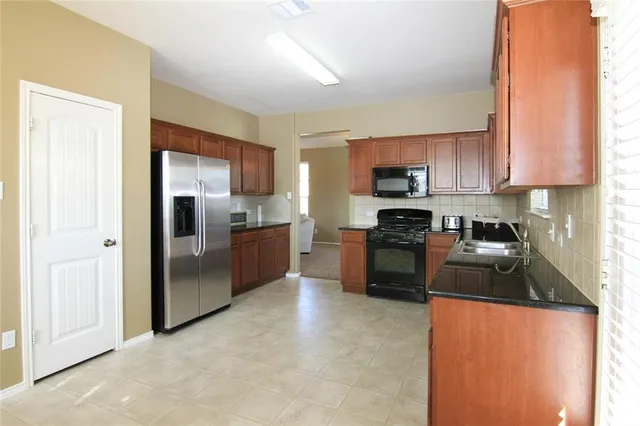 a kitchen with granite countertop a refrigerator and a sink