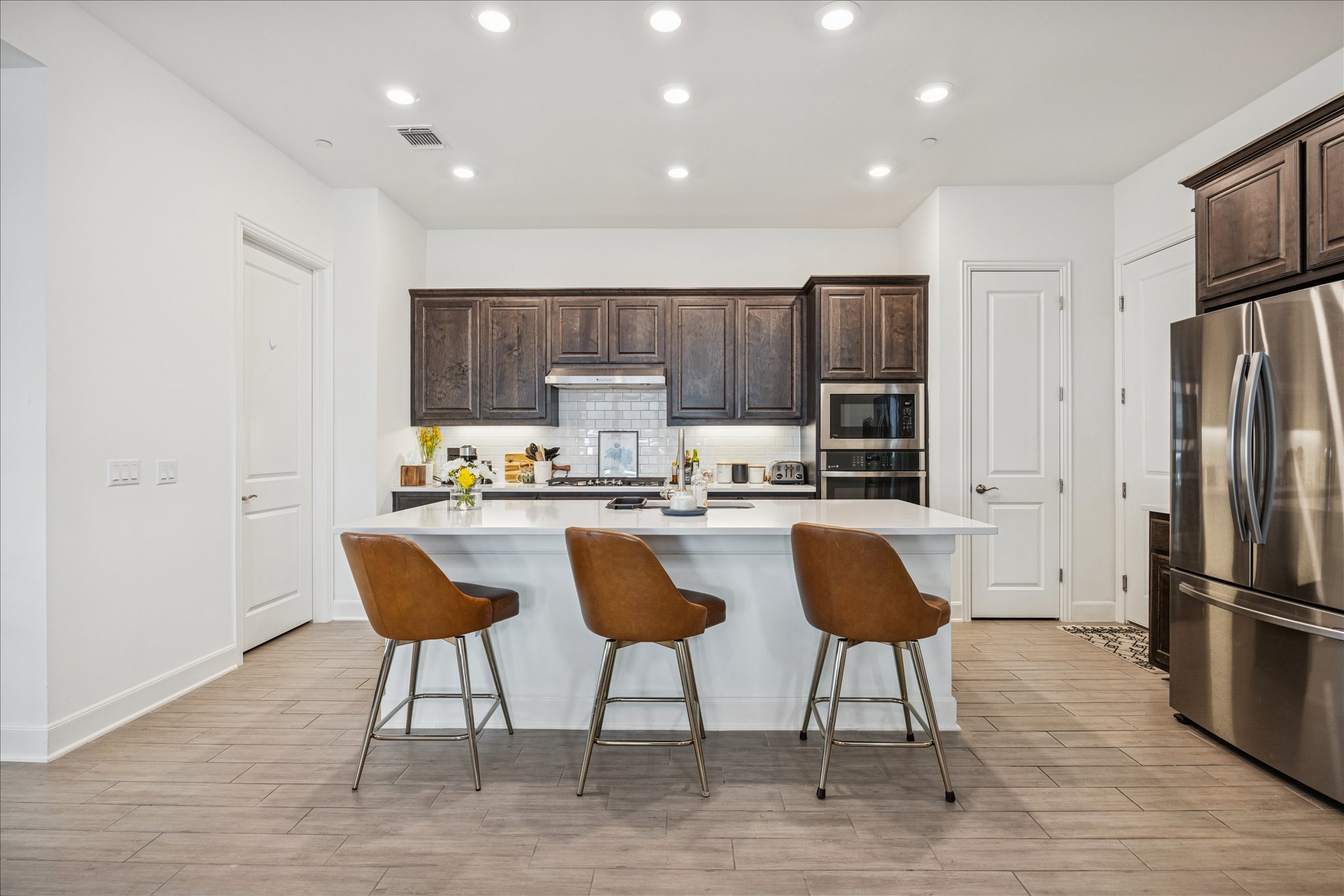 12507 Ayrshire Way, Unit 75 Austin, TX 78732 - Photo 13 of 40 Kitchen featuring dark wood finish cabinetry, recessed lighting, stainless steel appliances, an island with sink, and a breakfast bar area