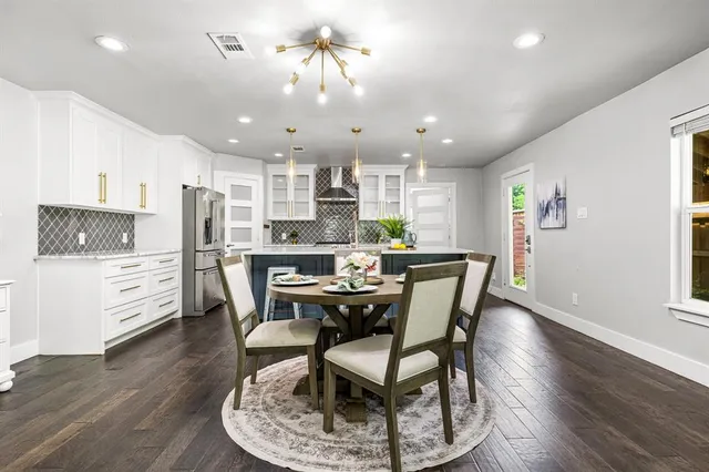 a dining room with stainless steel appliances kitchen island granite countertop a dining table chairs and a refrigerator