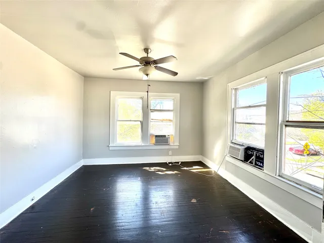 a view of empty room with wooden floor and fan
