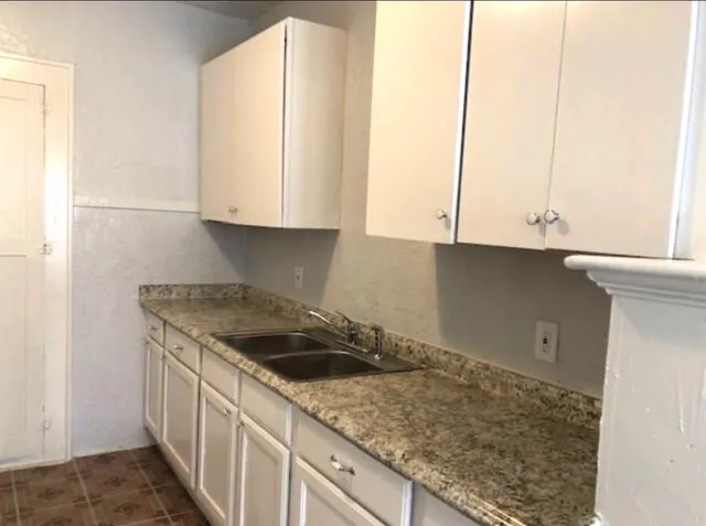 a kitchen with granite countertop white cabinets and a sink