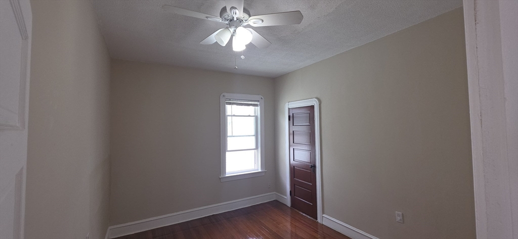 105 6th Street, Unit 3 Fall River, MA 02721 - Photo 7 of 10 an empty room with wooden floor chandelier fan and windows