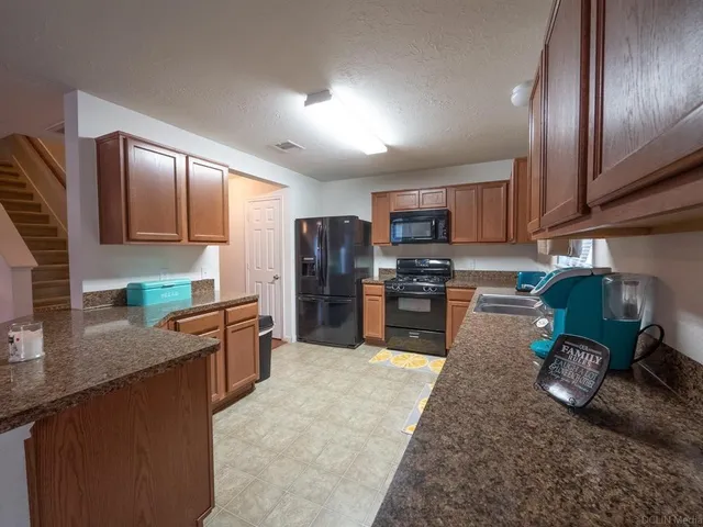 a kitchen with stainless steel appliances granite countertop sink stove refrigerator and cabinets