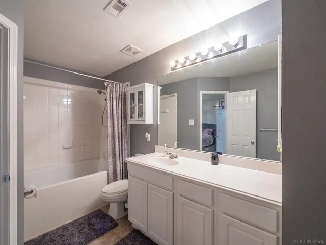 a bathroom with a double vanity sink toilet mirror and bathtub