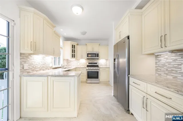 a kitchen with granite countertop white cabinets and stainless steel appliances