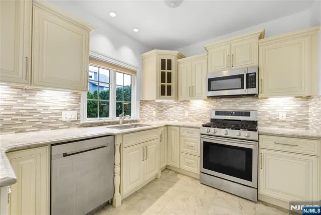 a kitchen with granite countertop cabinets stainless steel appliances and a window