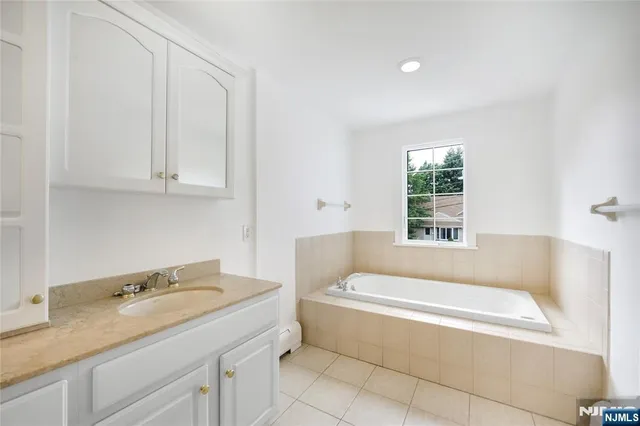 a bathroom with a granite countertop tub sink and mirror