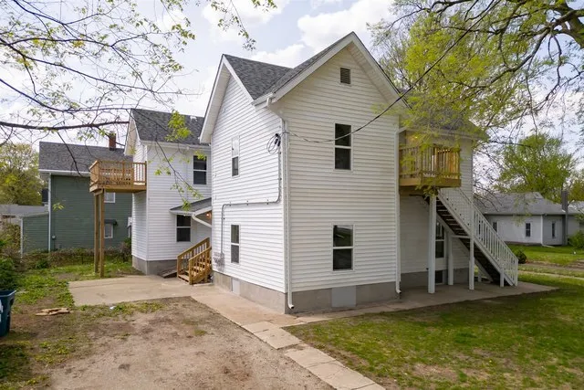 a view of a white house with a small yard and large tree