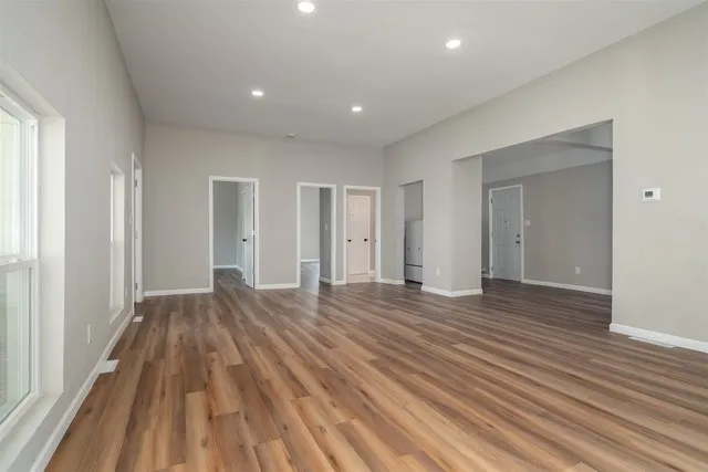 a view of an empty room with wooden floor and a window