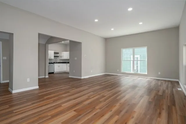 a view of empty room with wooden floor and windows
