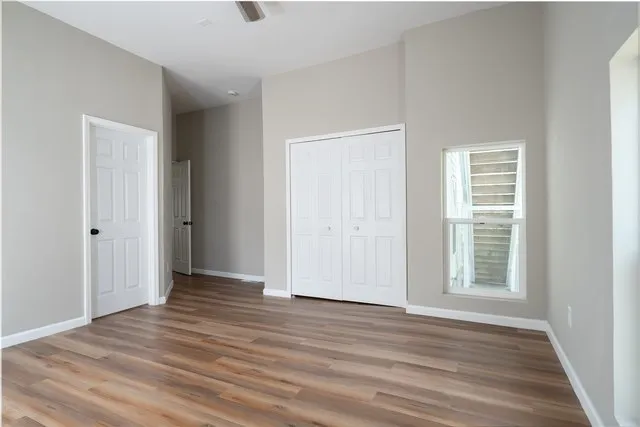 a view of an empty room with wooden floor and a window