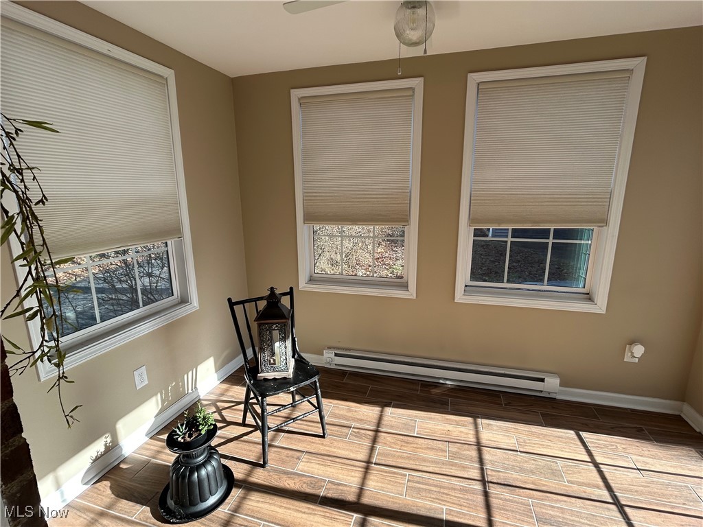 Sitting room featuring wood tiled floors, baseboard heating, and a ceiling fan