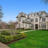 a view of a big house with a big yard and large trees
