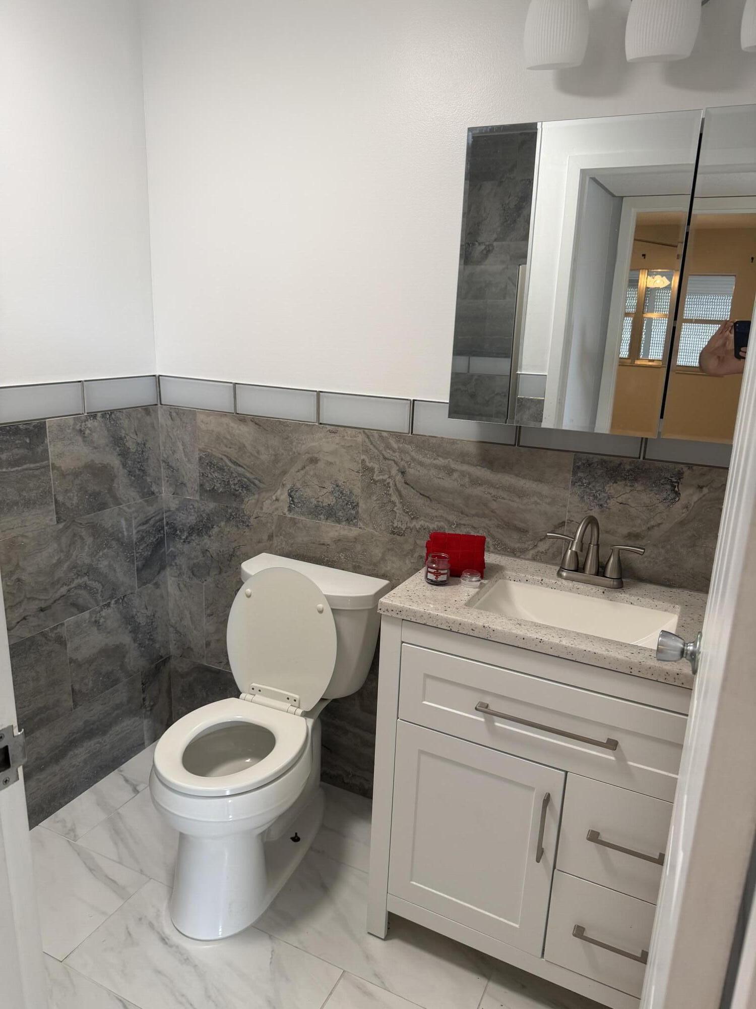 373 Monaco Way, Unit H Delray Beach, FL 33446 - Photo 6 of 9 a bathroom with a toilet sink and mirror