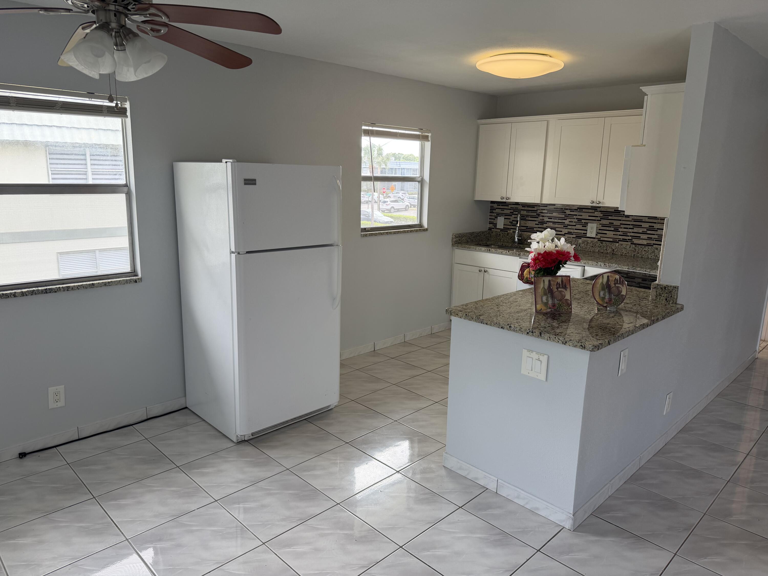 373 Monaco Way, Unit H Delray Beach, FL 33446 - Photo 8 of 9 a kitchen with a refrigerator and window