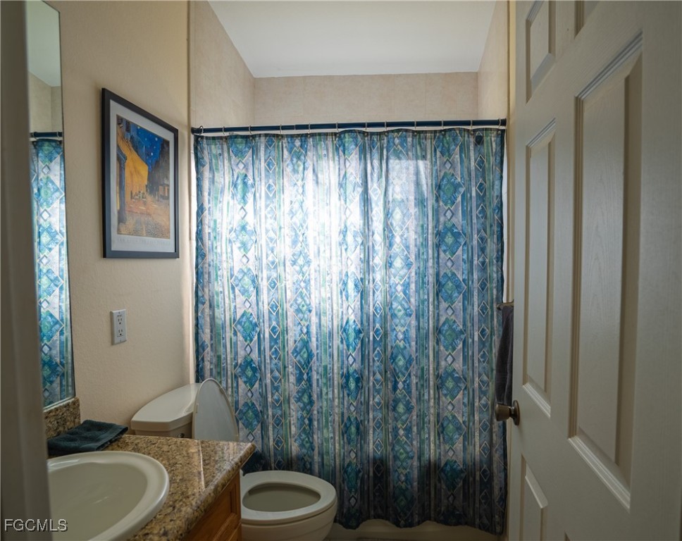 2516 13th Street Southwest Lehigh Acres, FL 33976 - Photo 10 of 16 a bathroom with a granite countertop sink toilet and shower