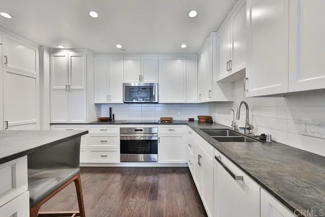 a large kitchen with stainless steel appliances granite countertop a stove a sink and a white cabinets
