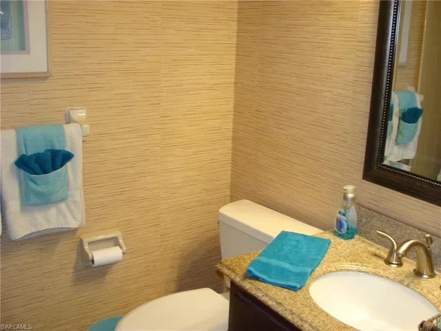 a bathroom with a granite countertop toilet sink and mirror