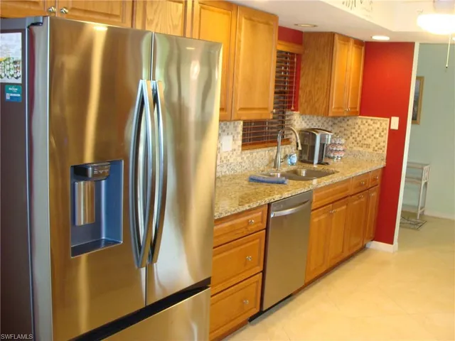 a kitchen with stainless steel appliances granite countertop a refrigerator a stove and a sink