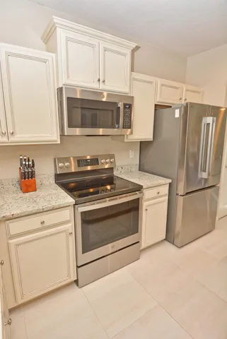 a kitchen with stainless steel appliances granite countertop a refrigerator a stove a sink a dining table and chairs with wooden floor