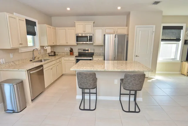 a kitchen with stainless steel appliances granite countertop a stove a refrigerator a sink a dining table and chairs