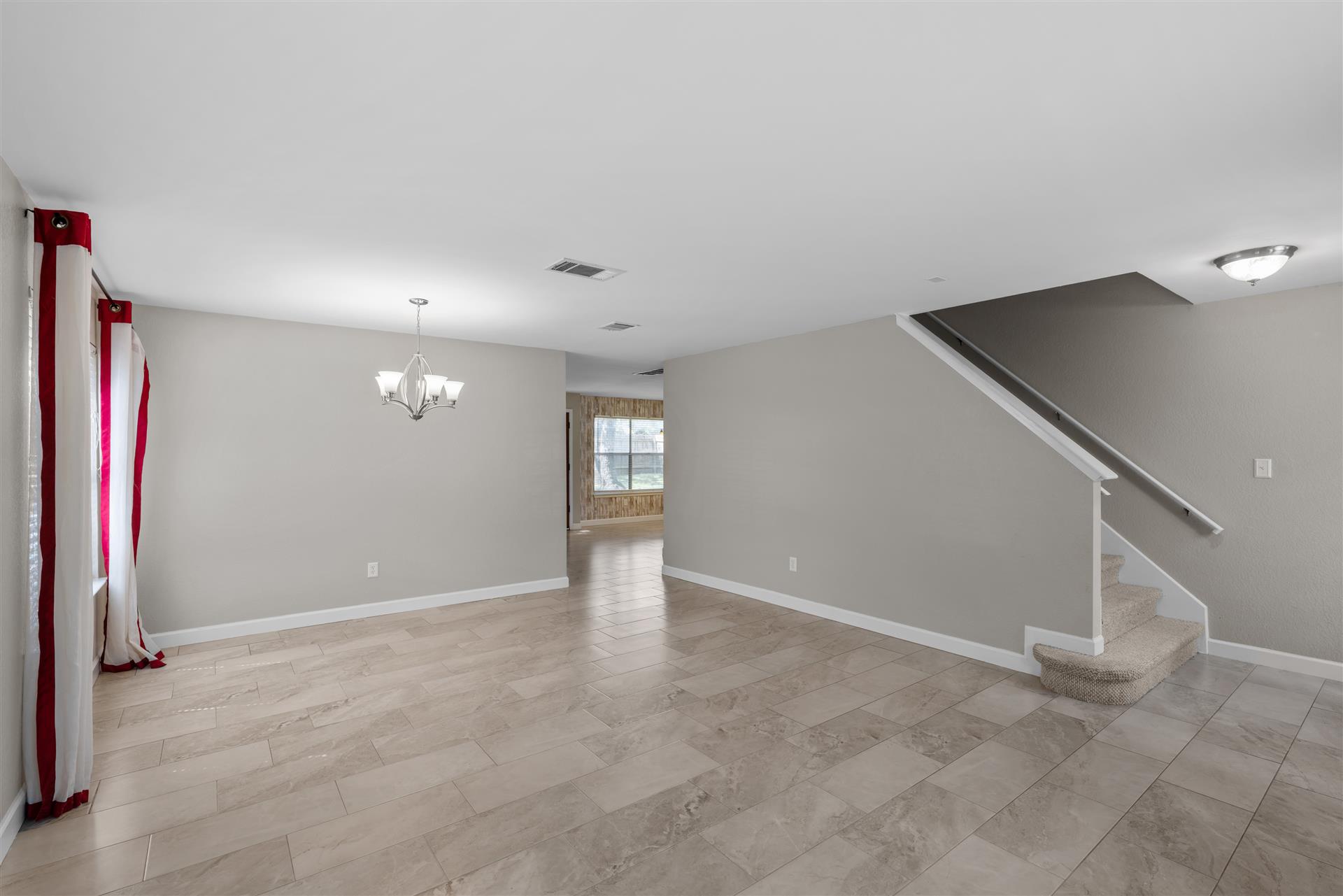 1710 Persimmon Road Cedar Park, TX 78613 - Photo 11 of 33 The open-plan living space features neutral walls, rectangular tile flooring, and a chandelier, creating an airy ambiance.