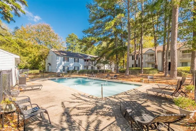 a view of swimming pool with outdoor seating and trees in the background