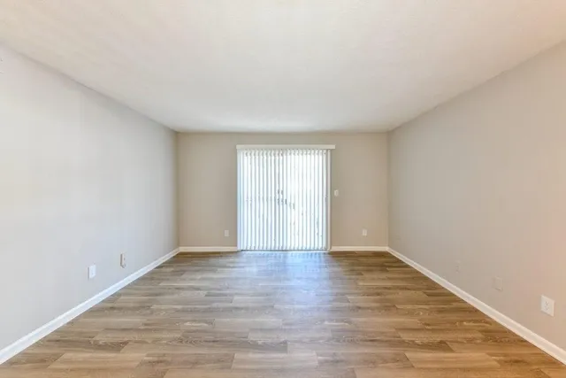 a view of an empty room with wooden floor and window