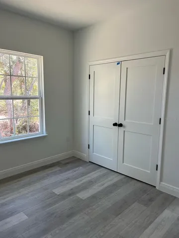 an empty room with wooden floor cabinet and windows
