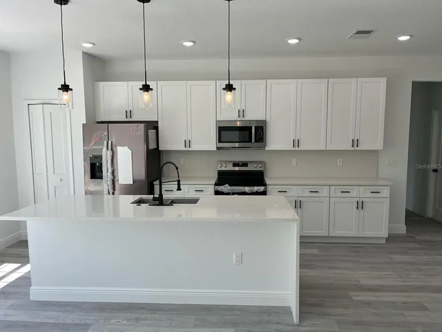 a kitchen with stainless steel appliances a refrigerator sink and white cabinets