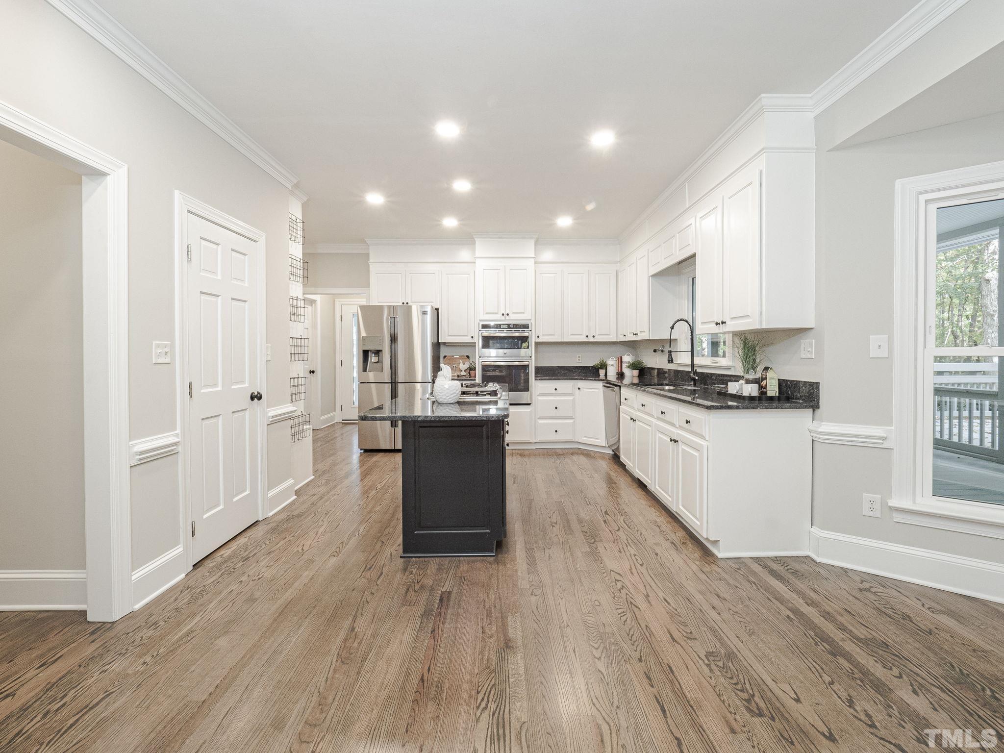 11936 Appaloosa Run East Raleigh, NC 27613 - Photo 11 of 30 a large kitchen with stainless steel appliances kitchen island granite countertop a stove a sink dishwasher and a cabinets with wooden floor