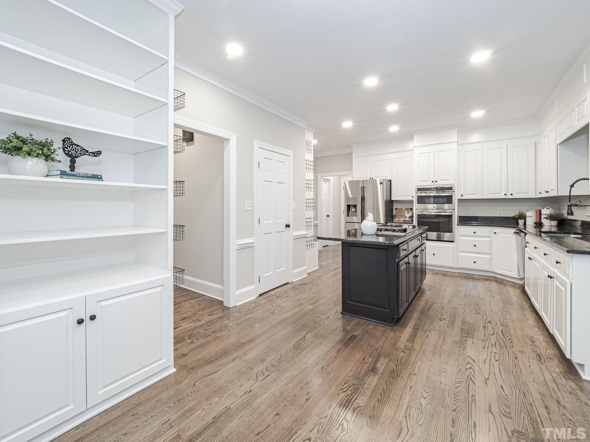 11936 Appaloosa Run East Raleigh, NC 27613 - Photo 12 of 30 a large kitchen with kitchen island a sink wooden floor and stainless steel appliances