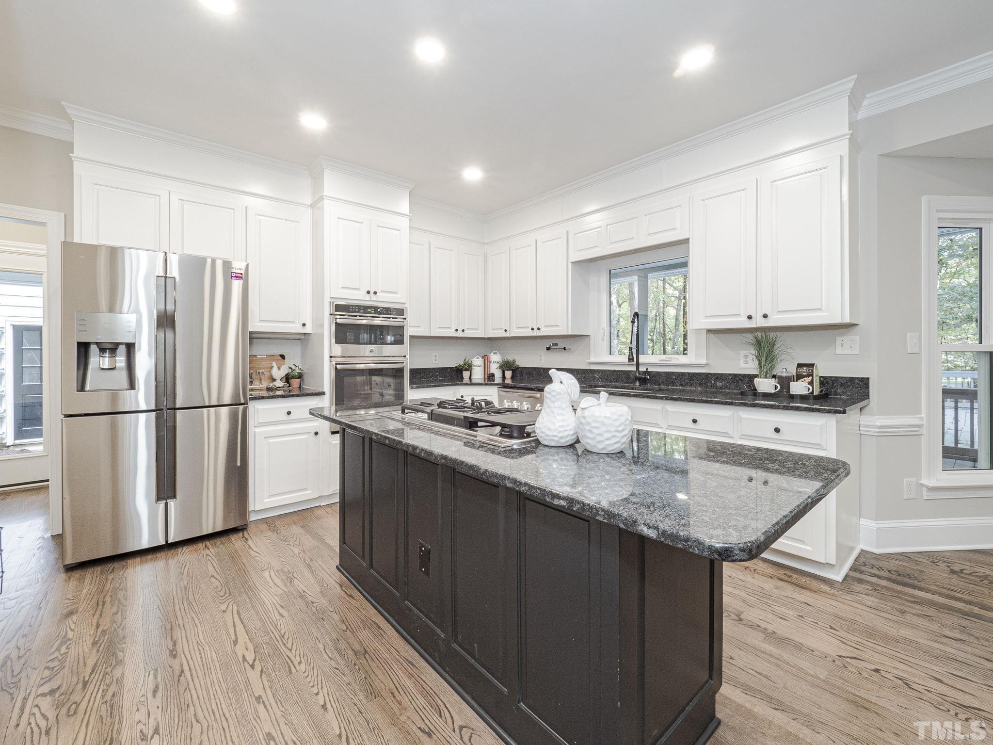 11936 Appaloosa Run East Raleigh, NC 27613 - Photo 13 of 30 a kitchen with stainless steel appliances granite countertop a refrigerator a sink dishwasher a stove and white countertops with wooden floor