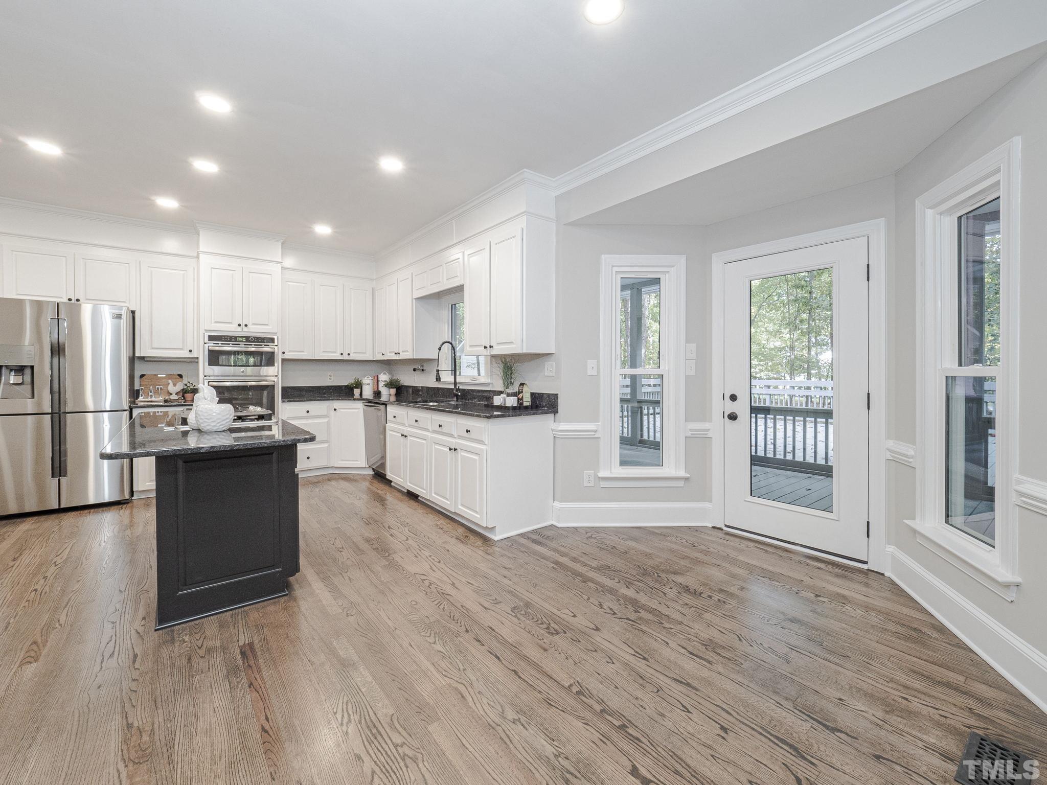 11936 Appaloosa Run East Raleigh, NC 27613 - Photo 10 of 30 a large kitchen with stainless steel appliances granite countertop a stove a sink dishwasher a refrigerator and white cabinets with wooden floor