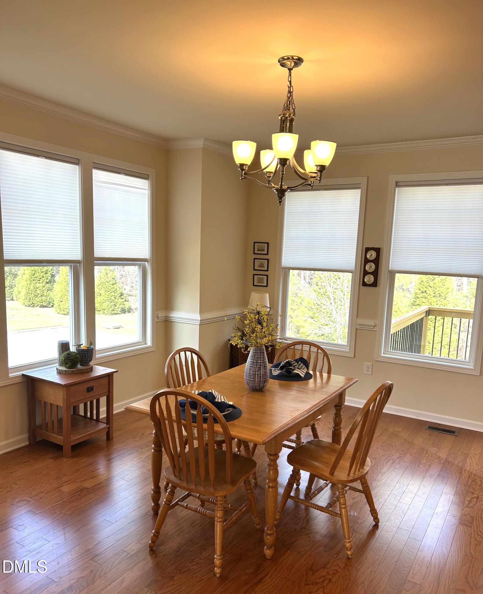 634 Edgewater Ridge Court Apex, NC 27523 - Photo 5 of 23 a dining room with wooden floor a chandelier a wooden table and chairs