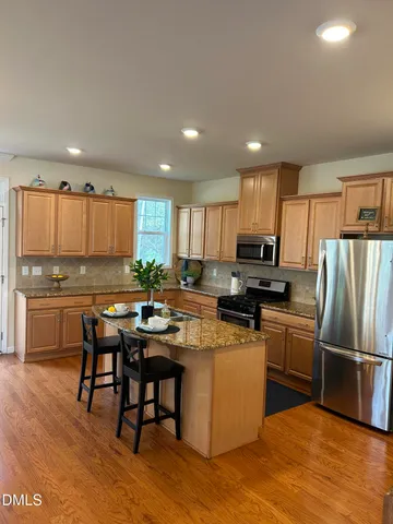 a kitchen with kitchen island granite countertop wooden floors and stainless steel appliances