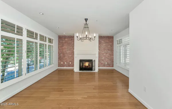 a view of a livingroom with a fireplace large windows and a chandelier