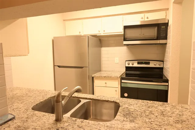 a kitchen with stainless steel appliances granite countertop a sink and a microwave
