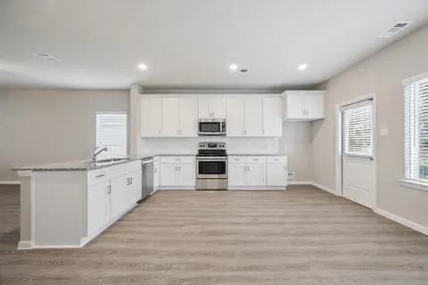 a large kitchen with granite countertop a large counter top stainless steel appliances and cabinets