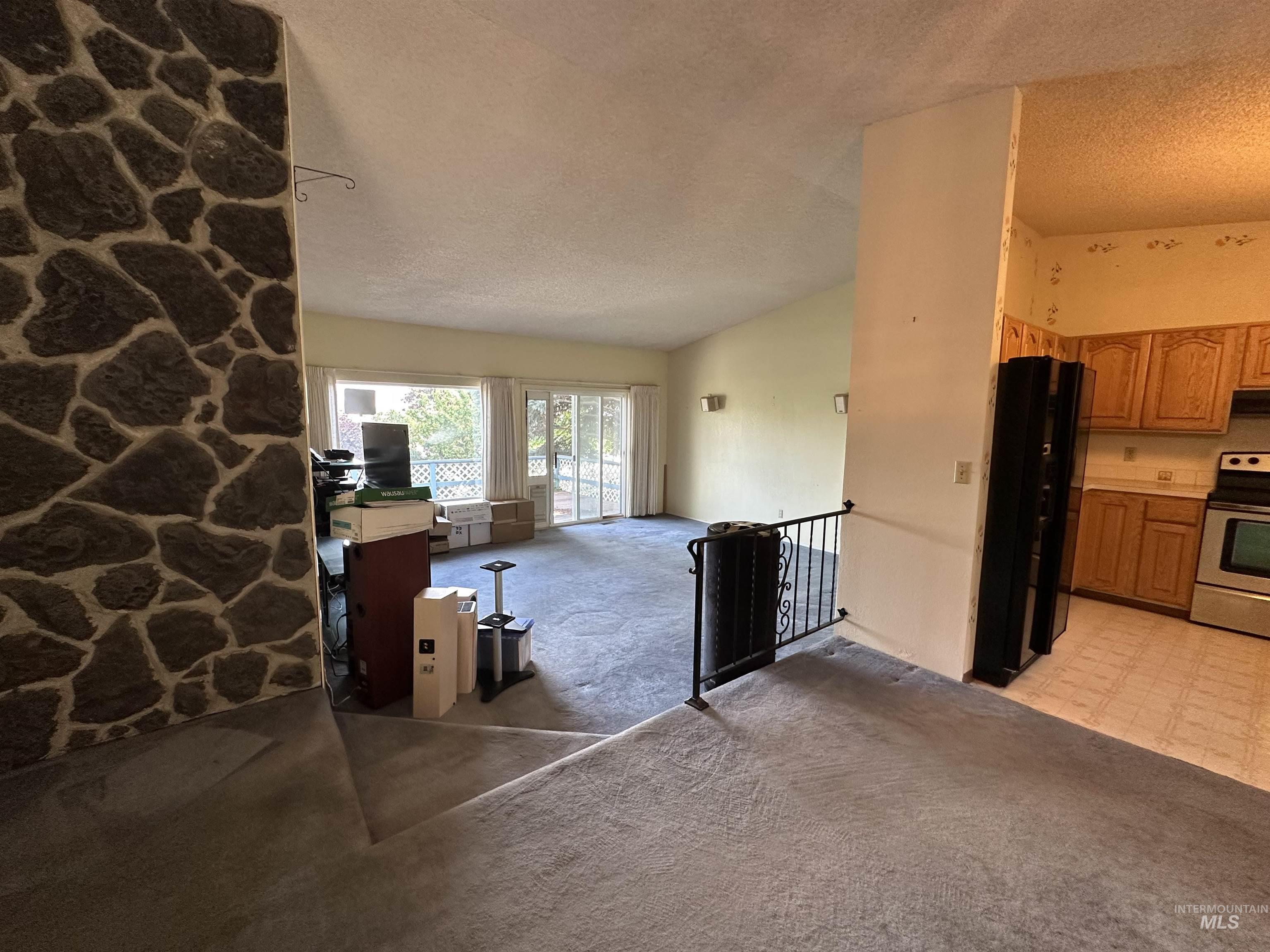 1620 6th Avenue Clarkston, WA 99403 - Photo 7 of 19 Open-concept living area featuring a vaulted ceiling and a stone accent wall