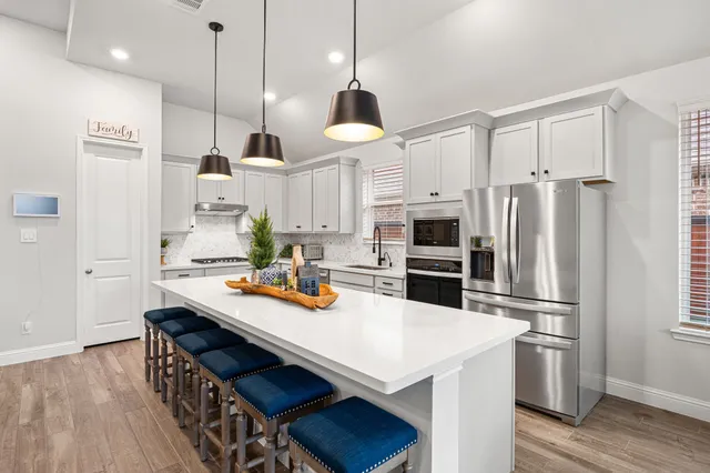 a kitchen with stainless steel appliances kitchen island granite countertop a stove a sink a center island a table and chairs