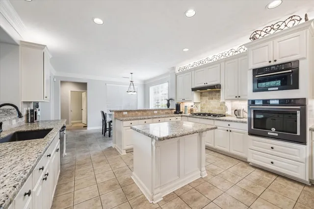 a large kitchen with stainless steel appliances granite countertop a stove and a sink