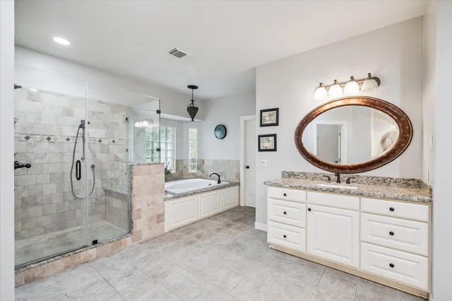 a spacious bathroom with a granite countertop sink mirror vanity and bathtub